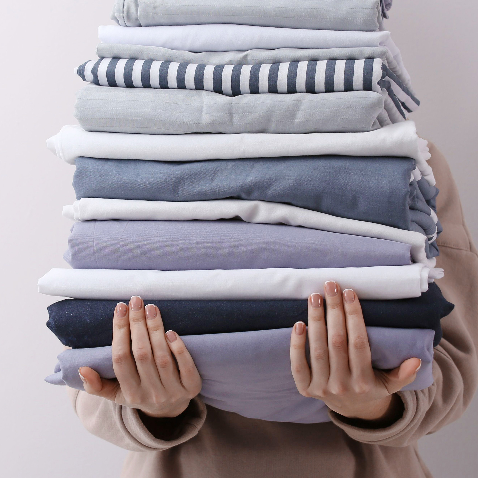 woman-holding-stack-of-linens A woman's hands holding a stack of clean linens