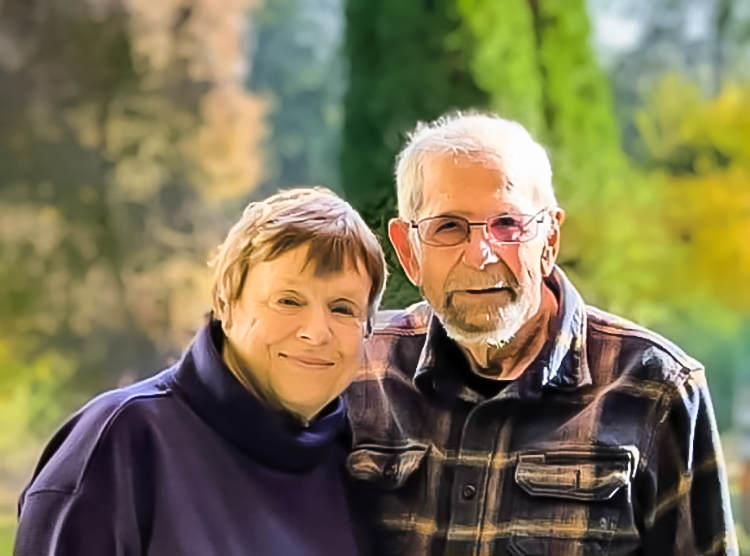 A senior couple poses for a portrait with trees in the background